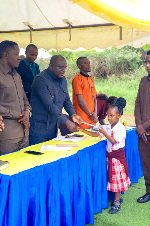 A pupil in formal uniform receiving a certificate from officials