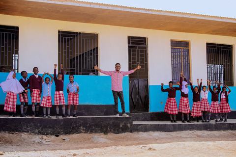Pupils cheering with their teacher outside the classroom block