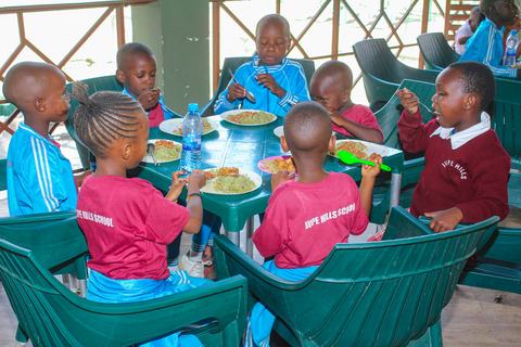 Pupils eating lunch together at green school tables