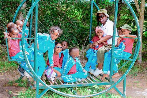 Pupils and a teacher playing together on a green swing