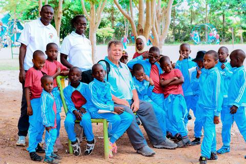 A visitor seated among Jupe Hills pupils and staff